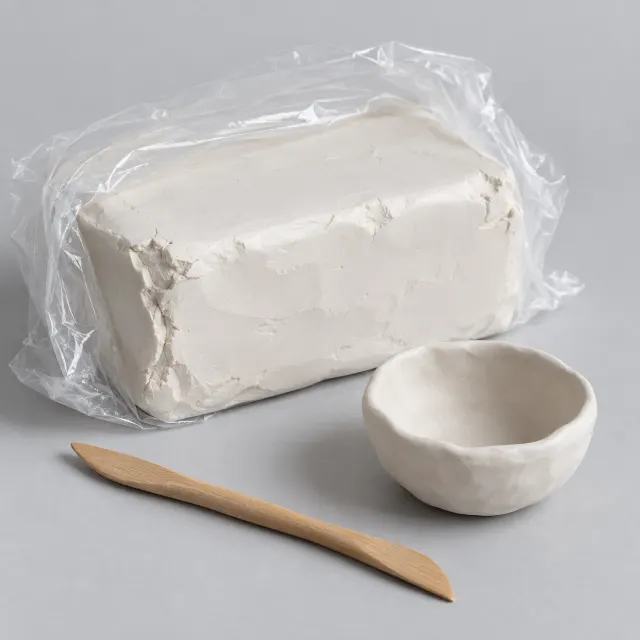 Bloque de arcilla blanca de secado al aire de cinco kilos envuelto en plástico, con un cuenco modelado al lado